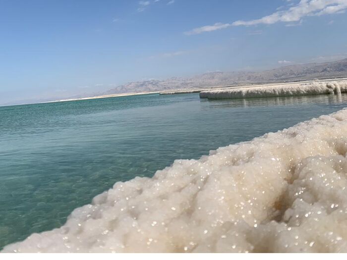 Mineral salt formations along a still turquoise inland sea.