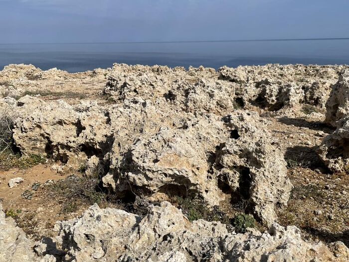 Limestone coastline meeting calm open sea.