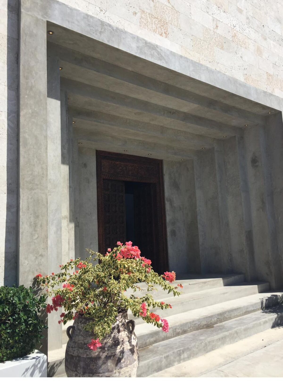 A monolithic stone entrance portico with layered concrete reveals.