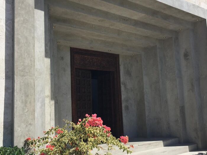 A stone portico entrance with deep recessed reveals and a single planted urn.